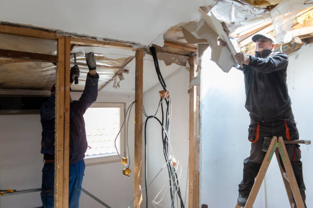 Двое рабочих монтируют гипсокартон на потолок во время ремонта дома.