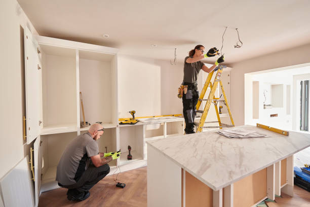 Двое мужчин устанавливают кухонные шкафы и светильники в проекте ремонта современного дома.